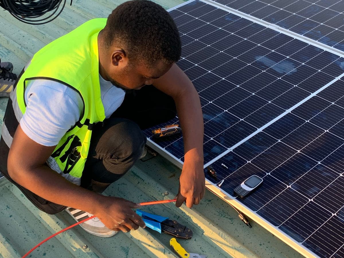 Installer crimping a solar cable connector on a rooftop array